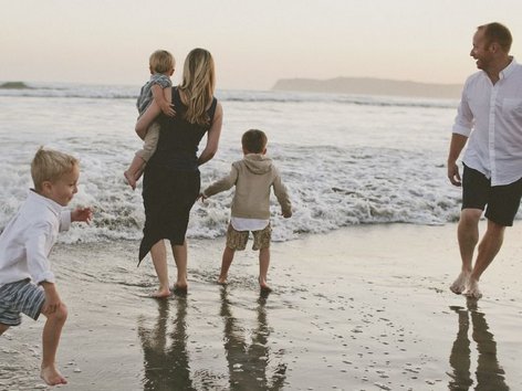 Teaser Foto Atopie; spazierende Familie mit drei Kindern beim Sonnenuntergang am Strand